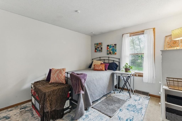 bedroom with a textured ceiling, carpet, baseboards, and visible vents