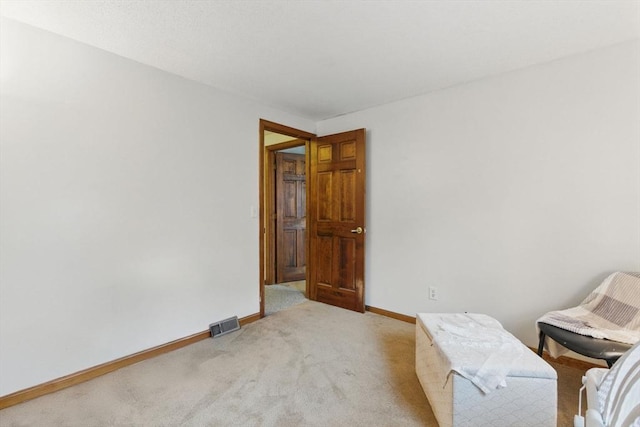 living area featuring baseboards, visible vents, and light colored carpet