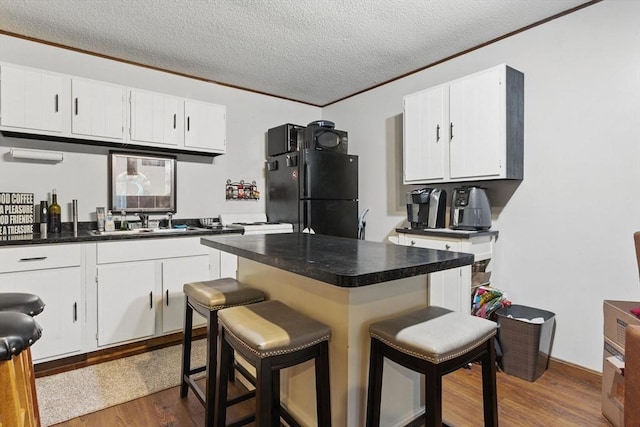 kitchen featuring freestanding refrigerator, ornamental molding, dark countertops, and a sink