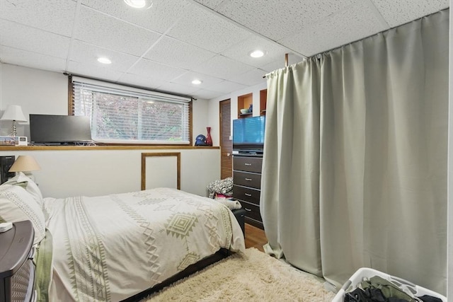 bedroom with a drop ceiling, wood finished floors, and recessed lighting