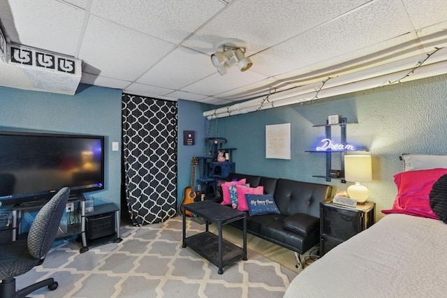 bedroom with a paneled ceiling and a textured wall