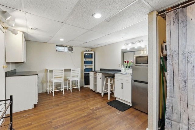 kitchen with wood finished floors, recessed lighting, white cabinetry, a drop ceiling, and appliances with stainless steel finishes