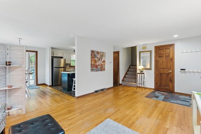 entrance foyer featuring light wood-type flooring, visible vents, baseboards, and stairway