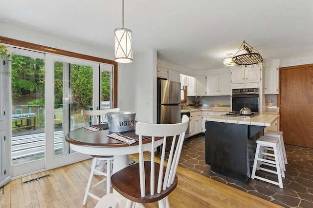 kitchen featuring tile counters, stainless steel appliances, white cabinetry, and light wood-type flooring