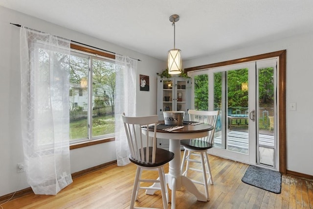 dining space with baseboards, light wood-style flooring, and a healthy amount of sunlight