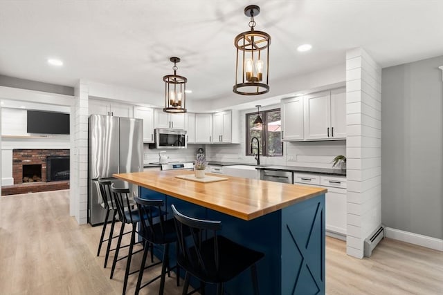 38 Manchaug Rd, Sutton, MA 01590 - kitchen with stainless steel appliances, butcher block countertops, a breakfast bar area, light wood finished floors, and white cabinetry