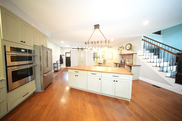 kitchen featuring a barn door, wooden counters, stainless steel appliances, and light hardwood / wood-style floors