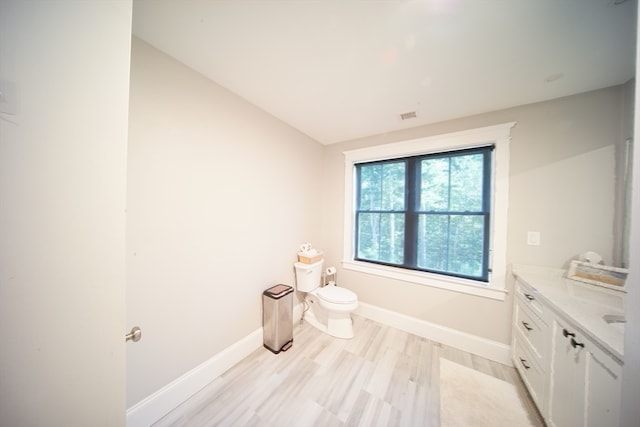 bathroom with lofted ceiling, vanity, toilet, and hardwood / wood-style flooring