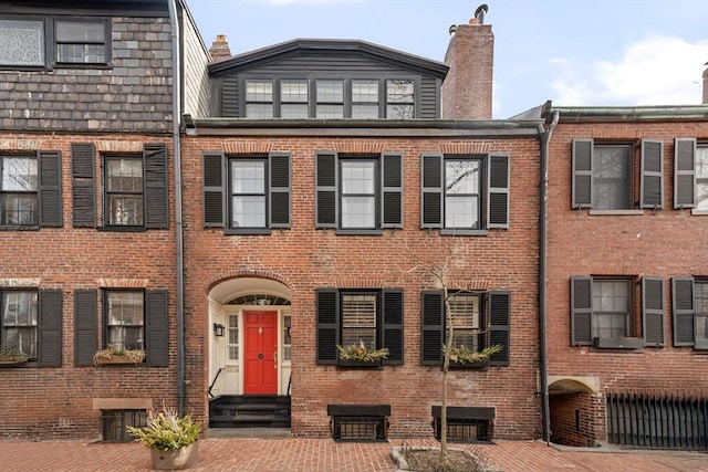 view of property featuring brick siding, a chimney, and entry steps