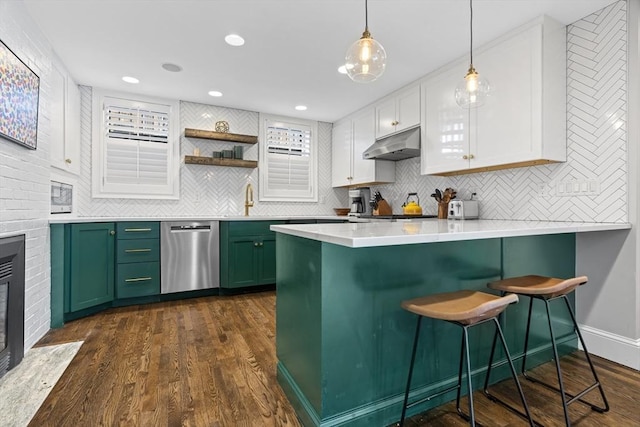 kitchen featuring under cabinet range hood, dishwasher, a breakfast bar, a peninsula, and green cabinetry