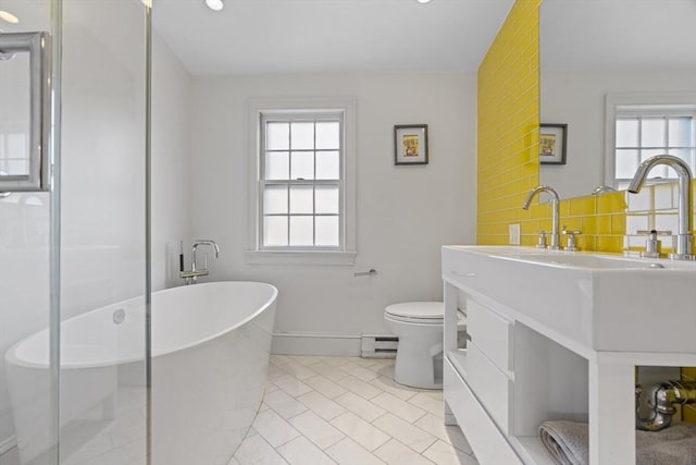 bathroom featuring baseboard heating, a healthy amount of sunlight, toilet, and decorative backsplash