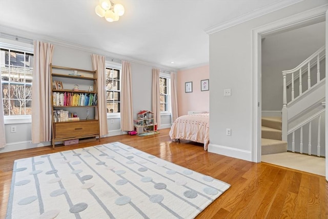 unfurnished bedroom featuring multiple windows, wood finished floors, baseboards, and ornamental molding