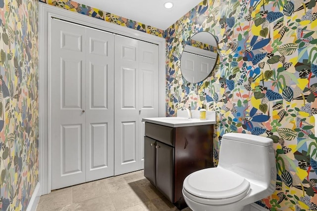 bathroom with wallpapered walls, toilet, a closet, tile patterned floors, and vanity