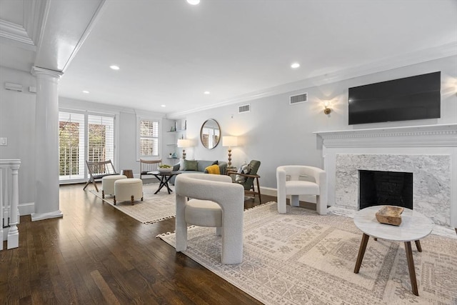 living area with visible vents, a fireplace, crown molding, and decorative columns