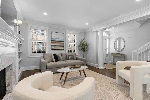 living room with a fireplace, wood finished floors, crown molding, and decorative columns