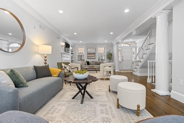 living area with visible vents, ornate columns, and wood finished floors