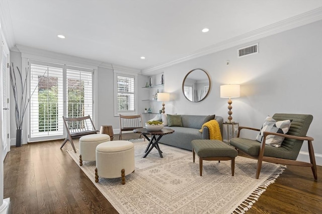 living area featuring baseboards, wood finished floors, visible vents, and ornamental molding