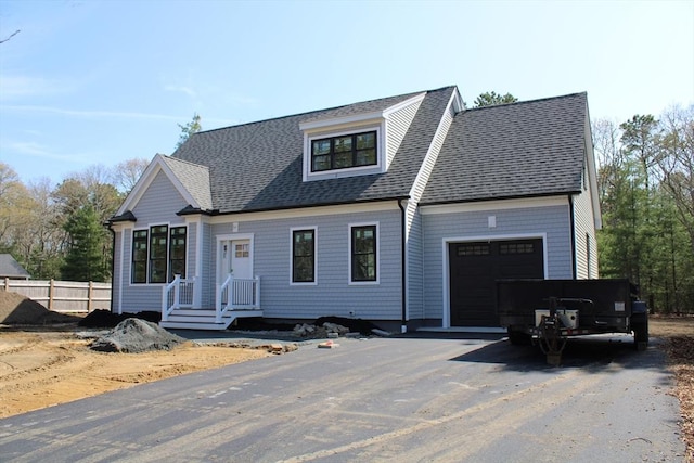 view of front facade with a garage, fence, roof with shingles, and aphalt driveway