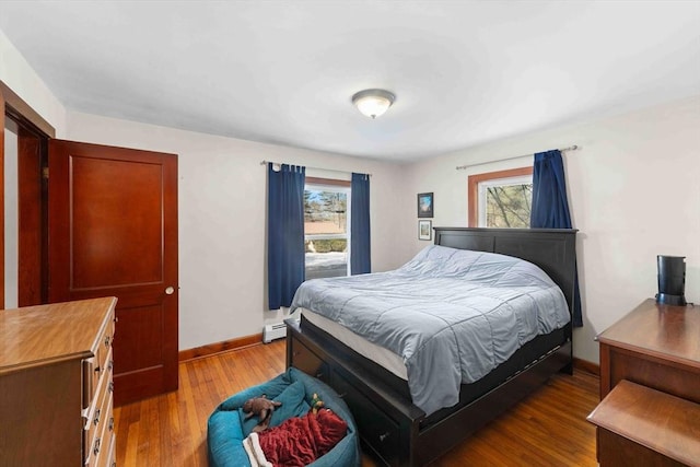 bedroom featuring multiple windows, baseboards, and wood finished floors