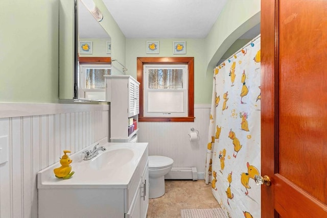 bathroom featuring toilet, curtained shower, wainscoting, baseboard heating, and vanity