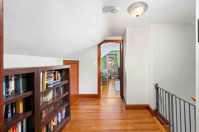 hallway featuring vaulted ceiling, baseboards, and wood finished floors