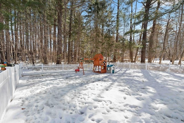 yard covered in snow with a fenced backyard and a playground