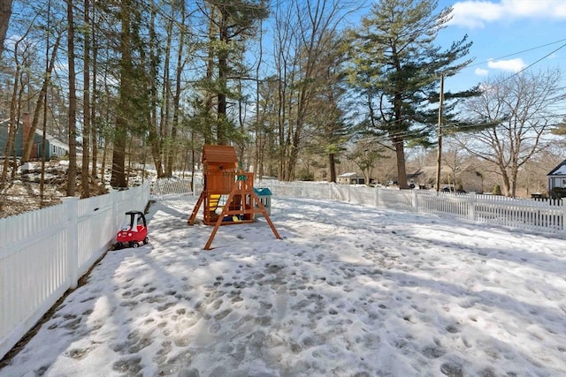 snow covered playground featuring a playground and a fenced backyard