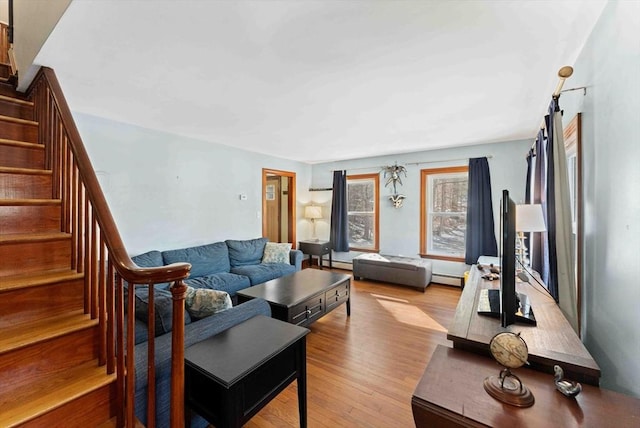 living area featuring stairway, baseboard heating, and wood finished floors