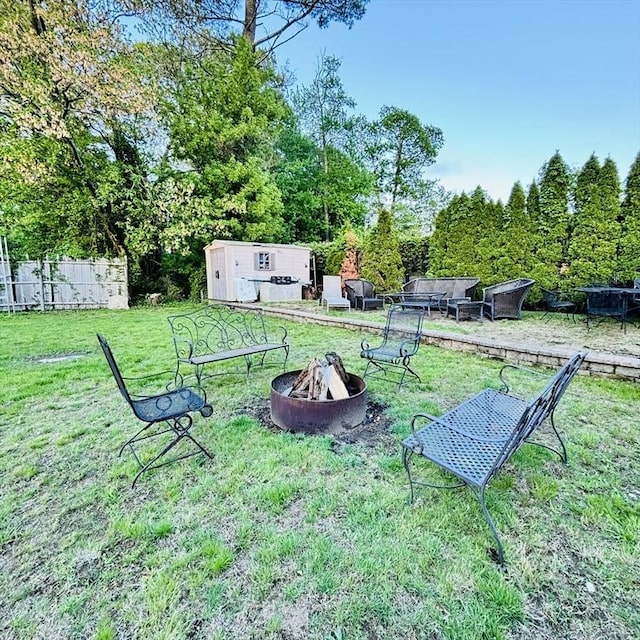 368 W St, Randolph, MA 02368 - view of grassy yard featuring a fire pit, a storage unit, an outdoor structure, and view of wooded area