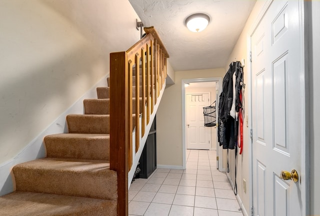 staircase with tile patterned flooring and a textured ceiling