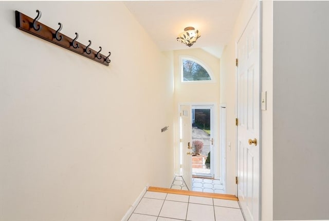 doorway with light tile patterned floors and high vaulted ceiling