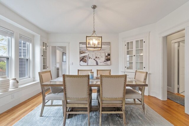 dining room featuring baseboards, light wood-style flooring, and a notable chandelier