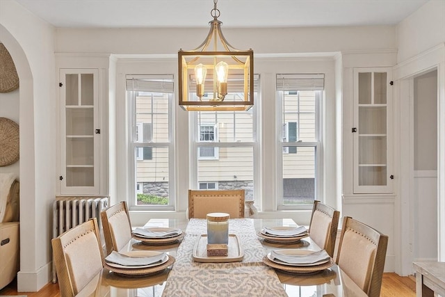 dining area with arched walkways, a notable chandelier, and a wealth of natural light
