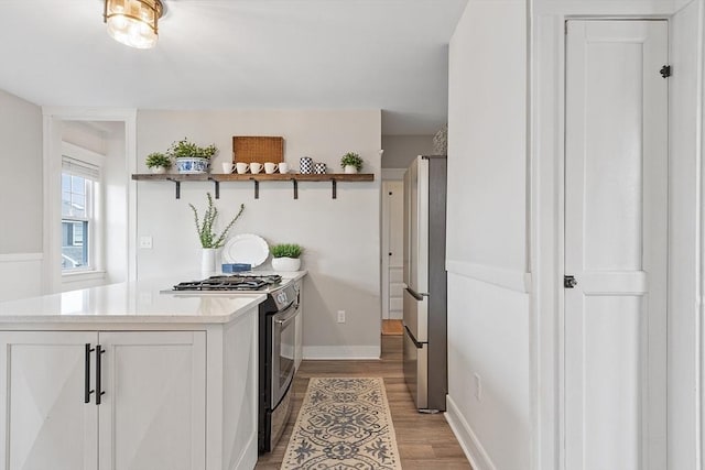kitchen featuring open shelves, baseboards, white cabinetry, light wood-style flooring, and stainless steel appliances