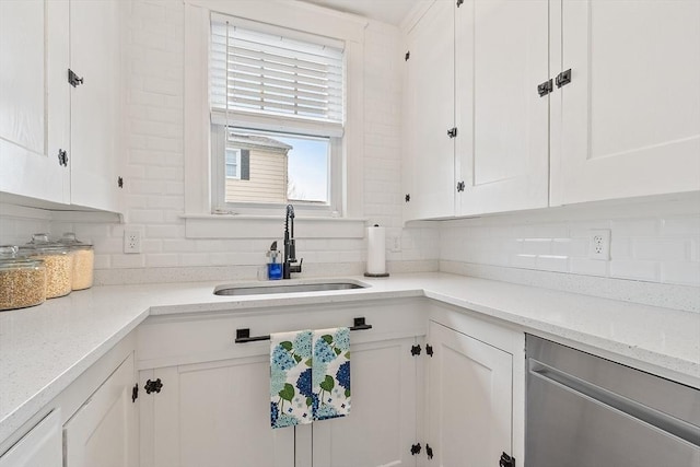 kitchen with a sink, backsplash, white cabinets, and light stone countertops