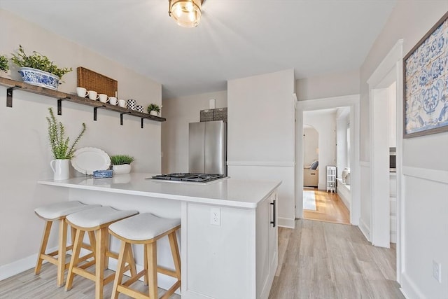 kitchen with light countertops, light wood finished floors, appliances with stainless steel finishes, and a breakfast bar area