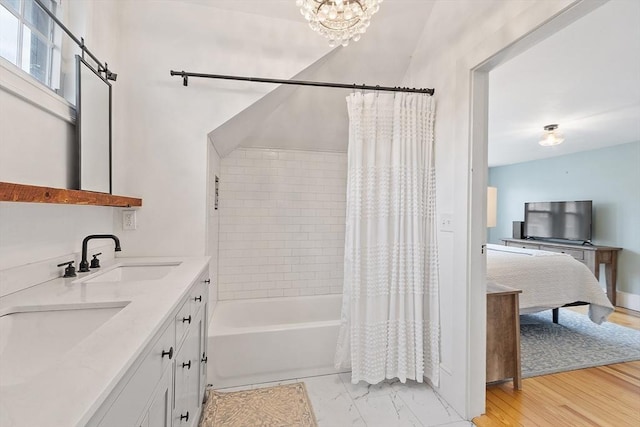 full bath featuring a notable chandelier, a sink, shower / bath combo, ensuite bath, and double vanity