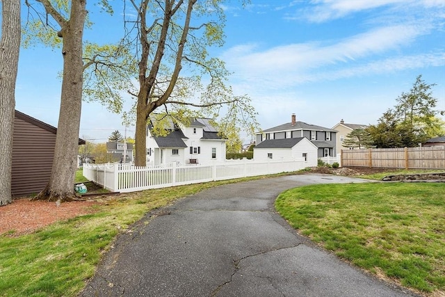 exterior space featuring fence, a yard, aphalt driveway, and a residential view