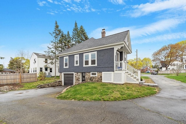 view of home's exterior featuring driveway, a chimney, a lawn, fence, and an attached garage