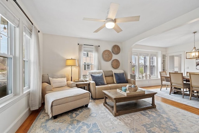 living room with arched walkways, baseboards, a ceiling fan, and wood finished floors
