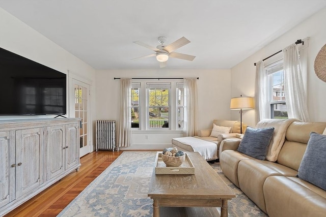 living room featuring radiator, ceiling fan, baseboards, and wood finished floors