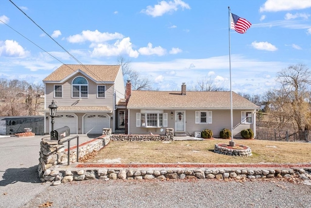 view of front of property featuring aphalt driveway, an attached garage, a front lawn, and fence