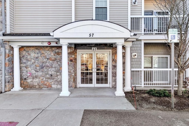 doorway to property with a porch, french doors, and stone siding