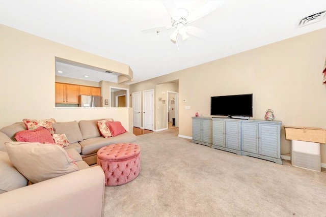 living room featuring visible vents, light colored carpet, a ceiling fan, and baseboards