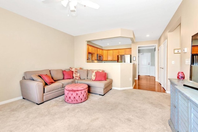 living room with a ceiling fan, recessed lighting, light colored carpet, and baseboards