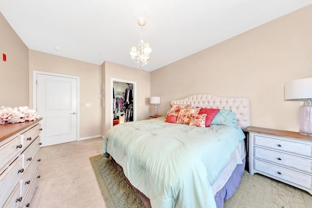 bedroom featuring a closet, baseboards, light colored carpet, a chandelier, and a spacious closet