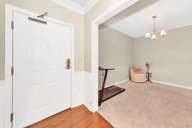 entrance foyer featuring crown molding, baseboards, a chandelier, carpet flooring, and wood finished floors