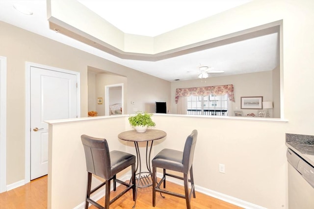 dining space with baseboards, light wood-style flooring, and a ceiling fan