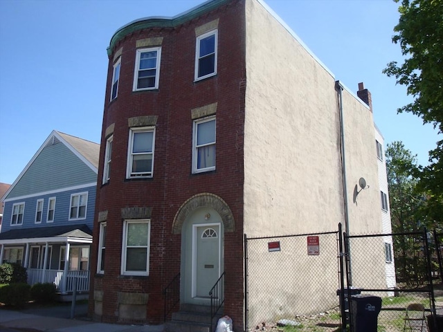 townhome / multi-family property featuring brick siding, fence, a gate, and entry steps