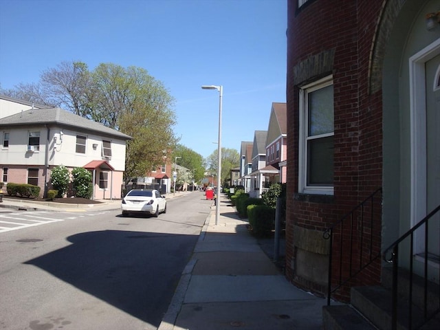 view of road featuring street lighting, a residential view, sidewalks, and curbs